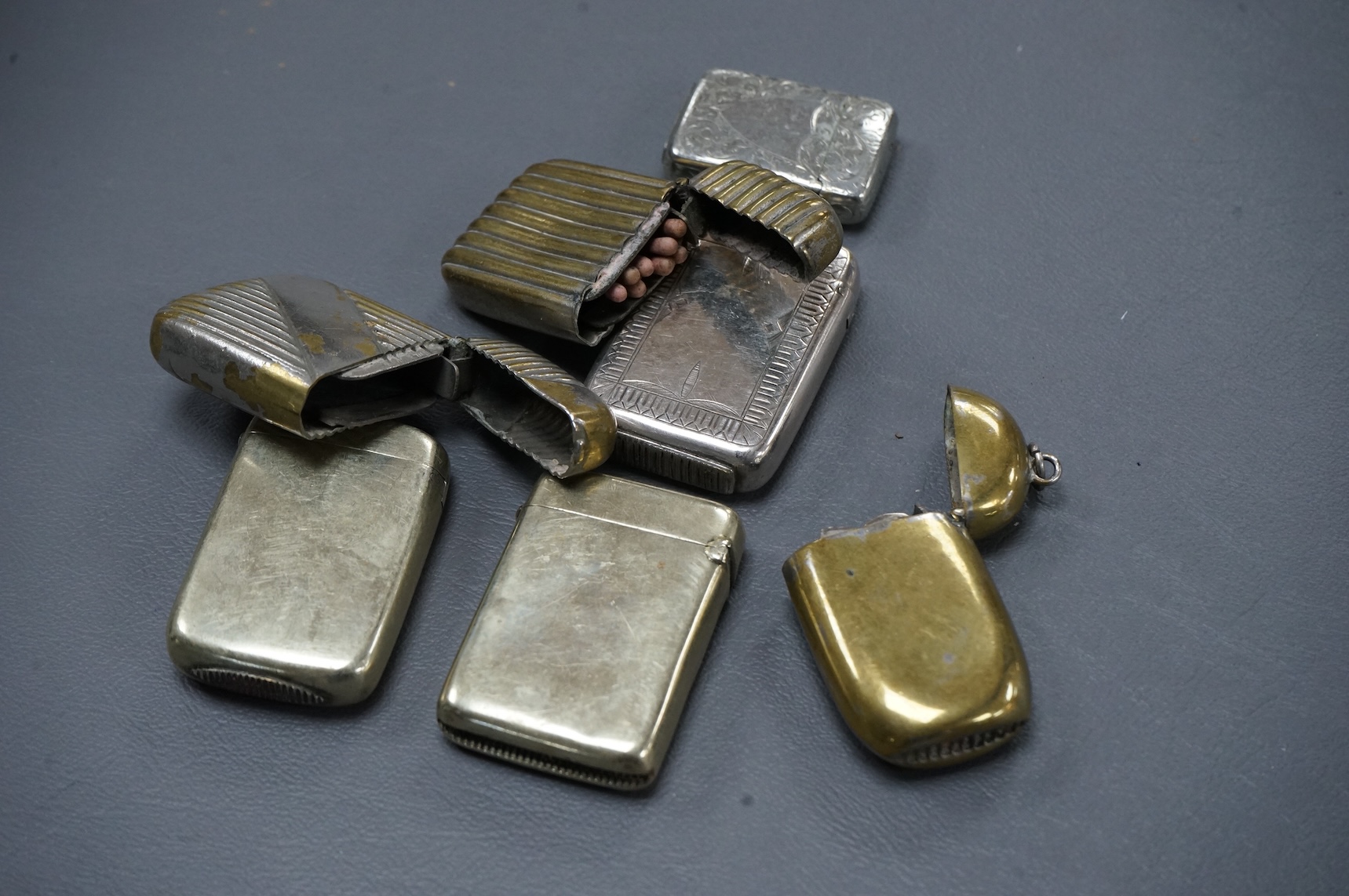 Seven base metal vesta cases, largest 6cm high